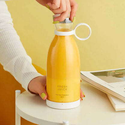 Portable electric juicer serving fresh orange juice on a table with books.