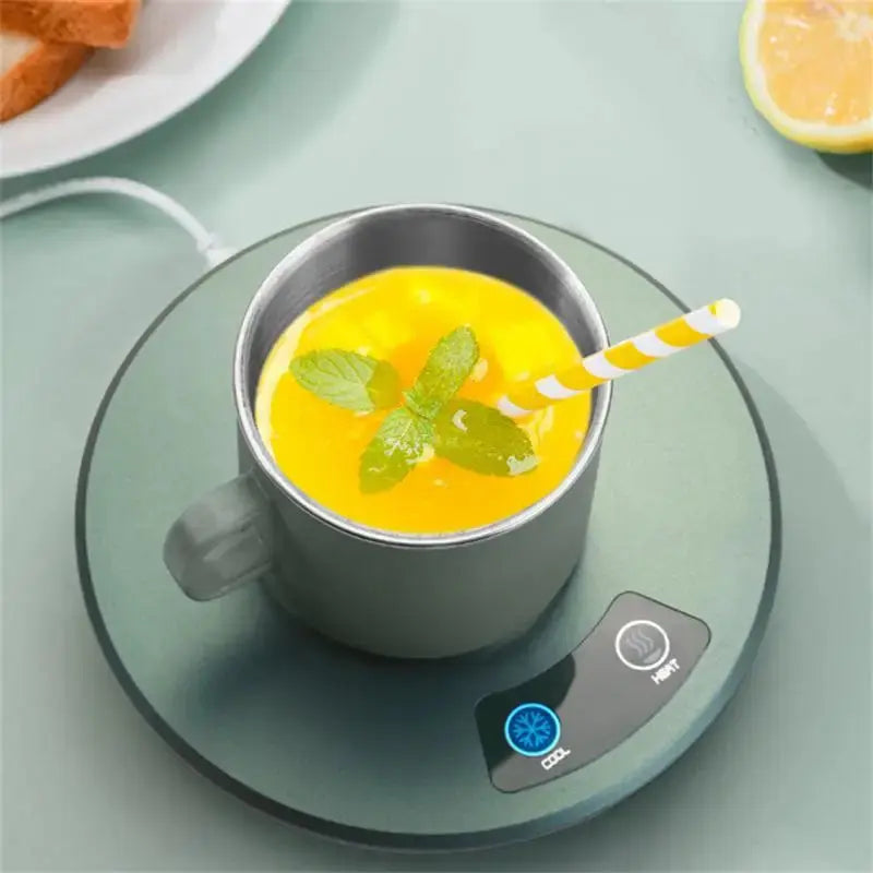 Cooling and heating mug on a charging pad with a yellow drink and striped straw.