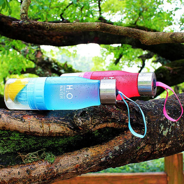 Fruit infusion water bottles on a tree branch with leafy background.