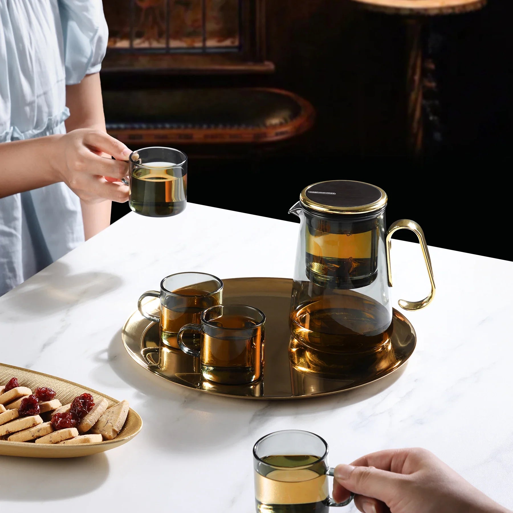 Magnetic switch tea maker with glass teapot and cups on marble table.