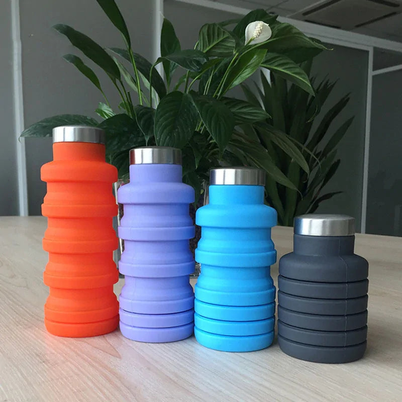 Collapsible water bottles in orange, purple, blue, and gray on a table.